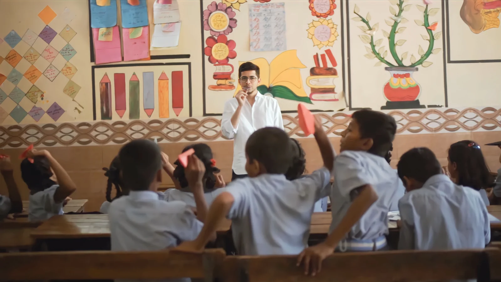 A teacher and schoolchildren in a colourful classroom
