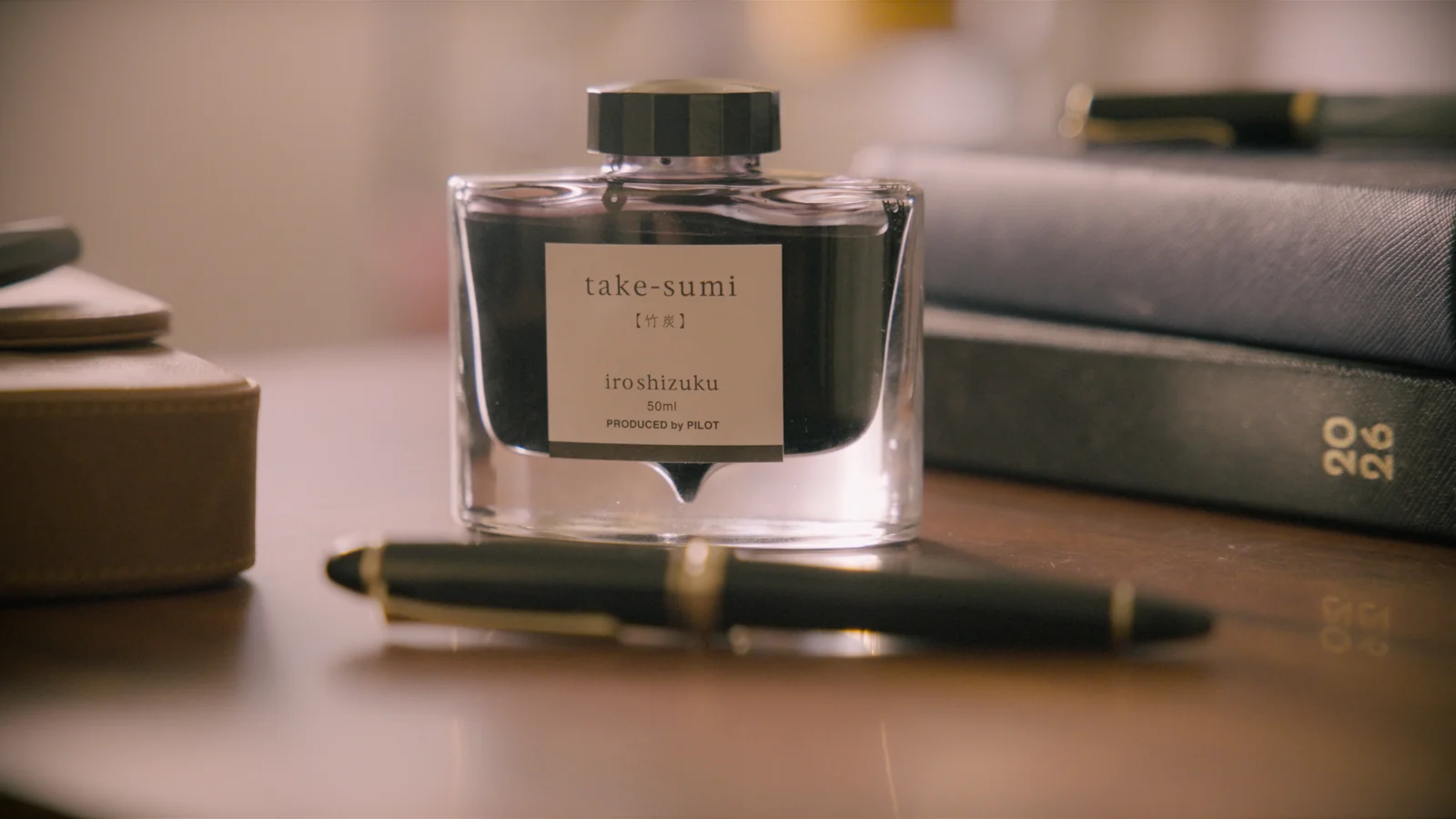 An ink bottle and fountain pen beside a notebook